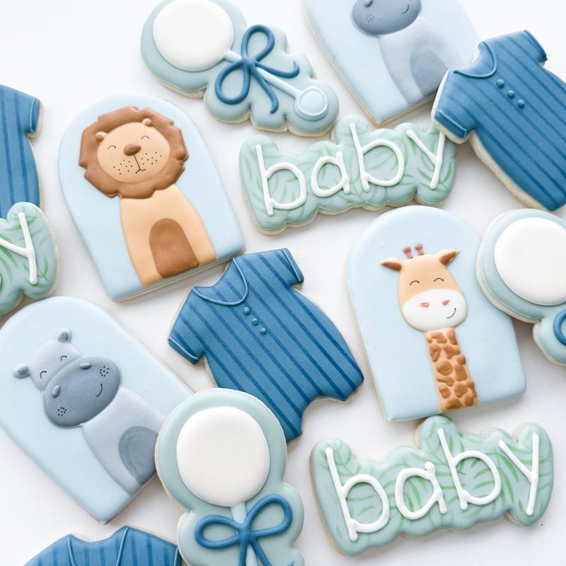 A baby-shower set in soft blue: onesies, a lion, a giraffe, a hippo and rounds lettered baby.