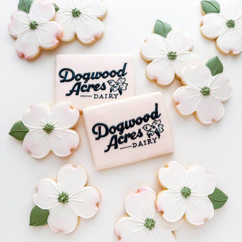A corporate launch set in white and green: dogwood blossoms and logo plaques for Dogwood Acres Dairy.