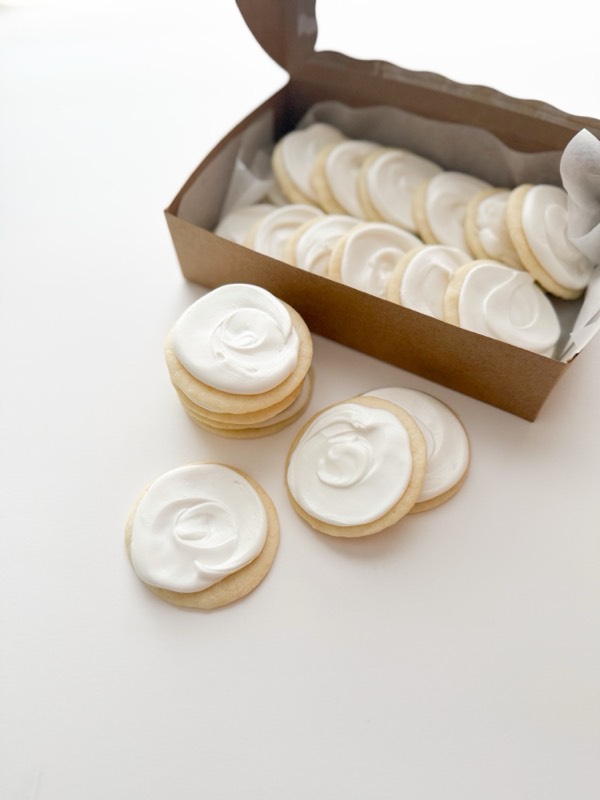 Round sugar cookies under smooth white icing, packed into a kraft box.