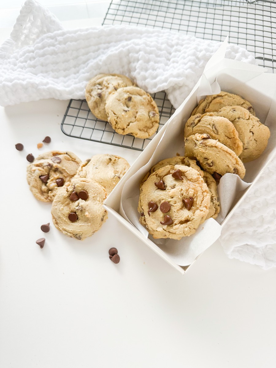Brown butter chocolate chip cookies packed into two white boxes with a cooling rack behind them.